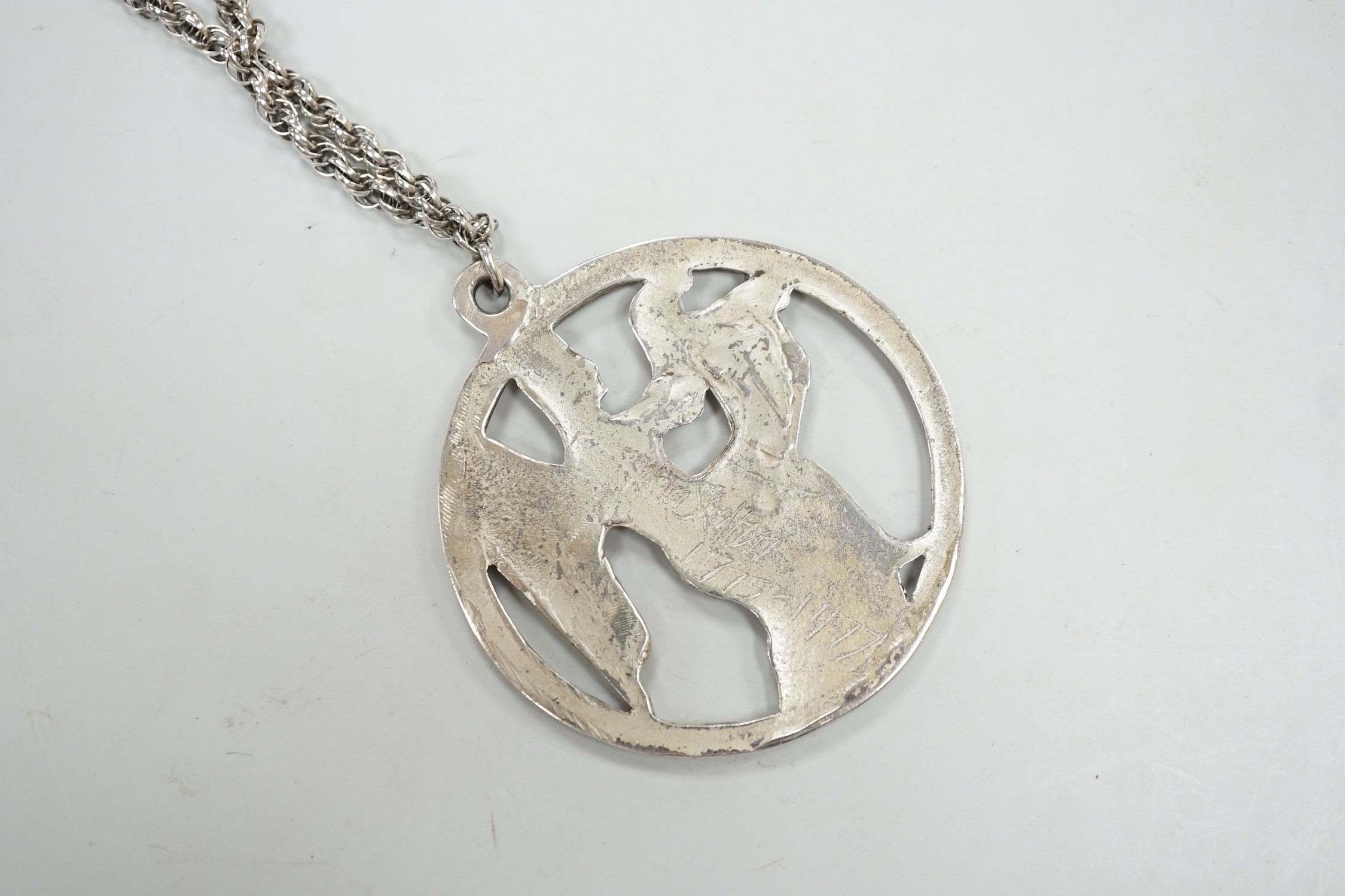 A late 1970's John Skelton silver pendant, depicting an angel with harp, diameter 63mm, on a sterling chain.